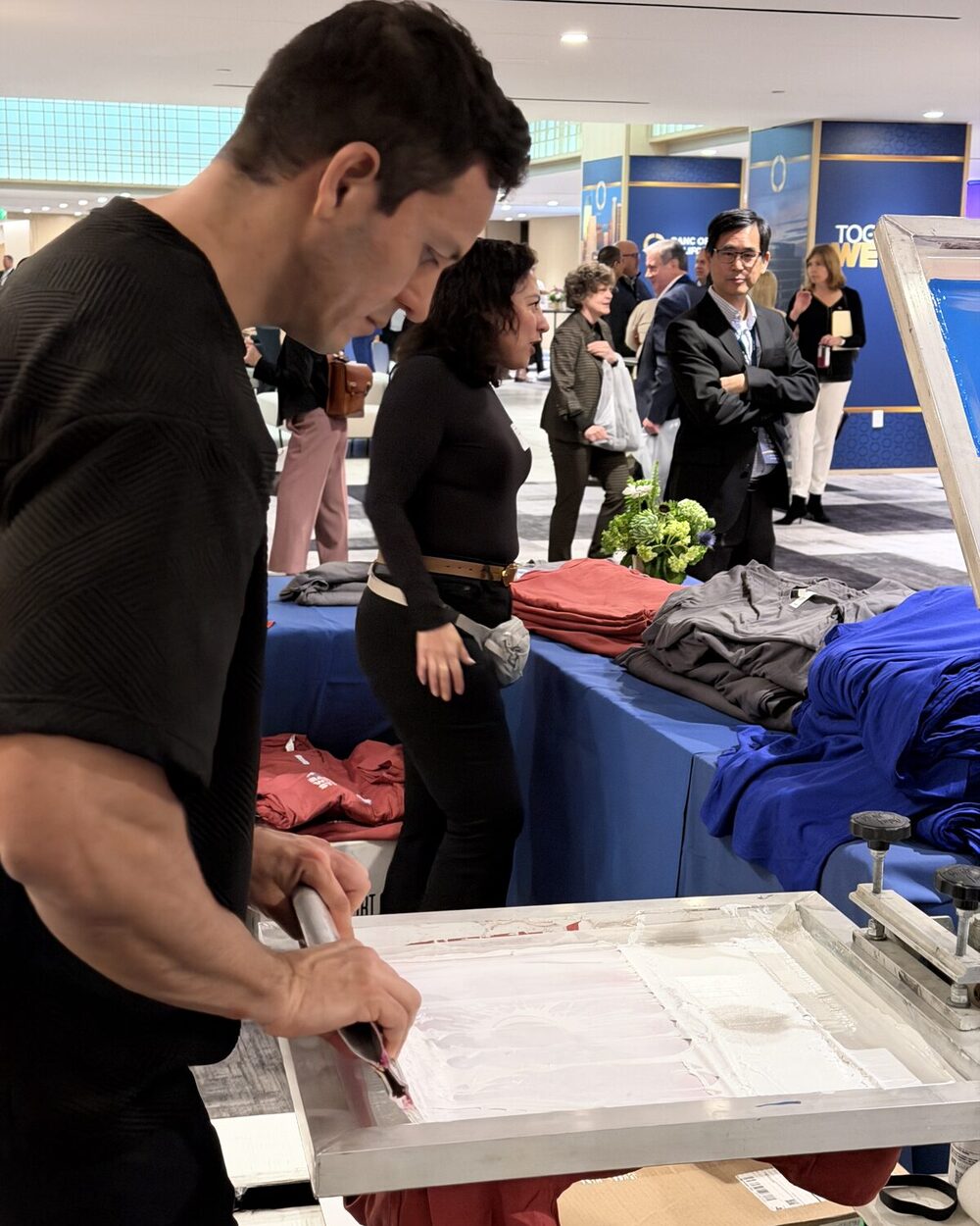 Merch Troop crew pulling a freshly pressed custom shirt off the heat press at an event shirt bar