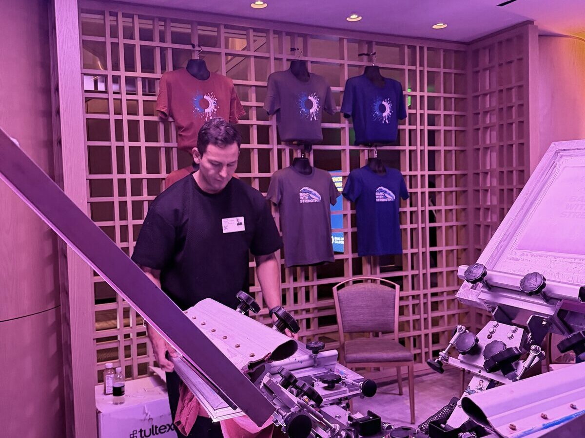 Custom shirt bar press station stacked with finished tees at an event